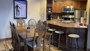 Una cocina moderna con armarios de madera, un microondas de acero inoxidable y una isla grande con taburetes de bar.