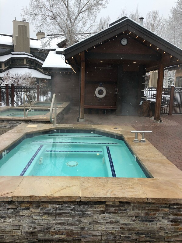 A swimming pool with stone walls and a wooden deck area.