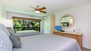 A bedroom with two beds, a ceiling fan, a large window with a view of palm trees, a wooden dresser, and a round mirror. - Ekahi 34F - Best Panoramic Ocean View!! (Kihei)
