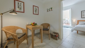 A room with a wicker chair, a wooden table with a fruit bowl, a floor lamp, and a bed with a white headboard. - San Lorenzo Terrace Duomo View, near the SMN station, Tram, Market. AC provided (Firenze)