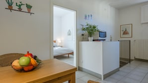 A small, clean room with a wooden table, a fruit bowl, a bed, and a kitchenette. - San Lorenzo Terrace Duomo View, near the SMN station, Tram, Market. AC provided (Firenze)