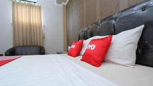 Una habitación de hotel con una cama, una silla y una cortina.