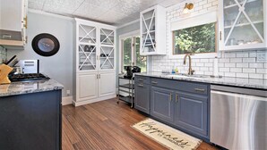 Une cuisine avec des meubles blancs, un lave-vaisselle en acier inoxydable et un plancher en bois.