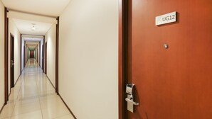 Un pasillo de hotel con un cartel que dice "UG12" en una puerta, que conduce a una habitación.
