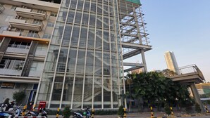 Un edificio moderno con fachada de vidrio, varios pisos y una escalera a la derecha.