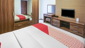 Habitación de hotel con una cama grande, un armario con espejo, un escritorio y un televisor, además de una alfombra estampada.