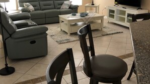 A living room with a sofa, chairs, a coffee table, a TV, and a dining area.