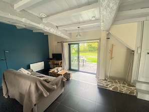 Una sala moderna con un sofá, una televisión y una zona de comedor con sillas y una mesa.