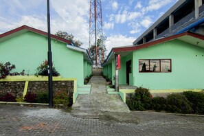 A pathway leading to a row of green buildings with a staircase. - OYO 1701 Bagus Inn (Berastagi)