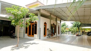 A covered outdoor area with a tiled floor, a tree, and a motorcycle parked nearby.