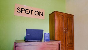 A wooden cabinet with a laptop on top and a sign that reads "SPOT ON" on the wall.