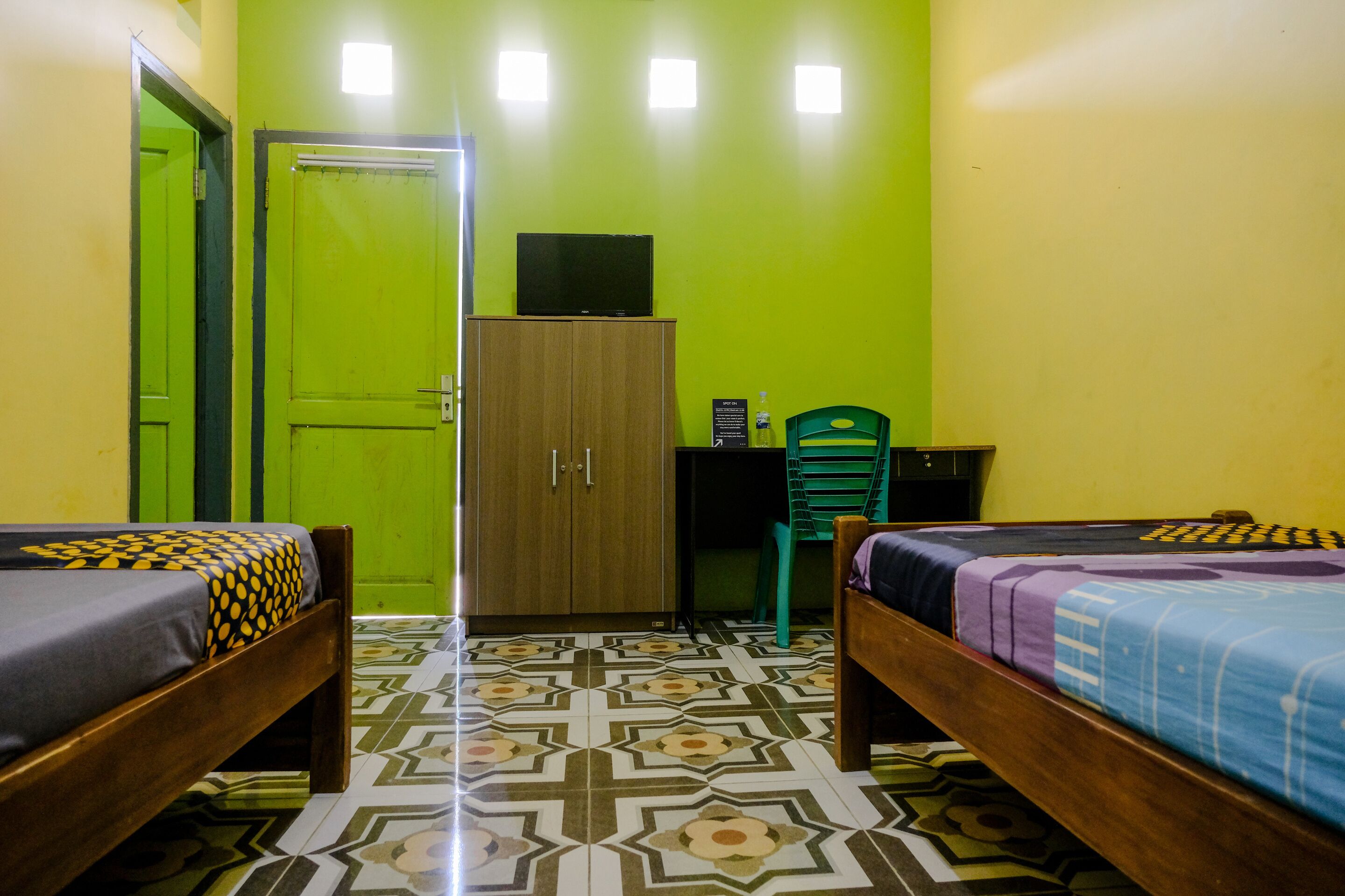 Una habitación con dos camas, un armario, un escritorio y una silla.