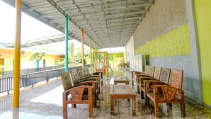 A covered outdoor seating area with wooden furniture and a tiled floor.