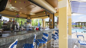 A covered outdoor bar area with a pool in the background. - Taragon by VillaDirect (Kissimmee)