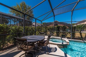 A covered outdoor area with a pool, seating, and a hot tub.