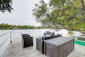 An outdoor deck with wicker furniture, a wooden deck, and a view of a body of water.