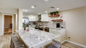 A modern kitchen with a marble island, stainless steel appliances, and a built-in oven. - Breathtaking sunsets and sunrises! (Indian Rocks Beach)