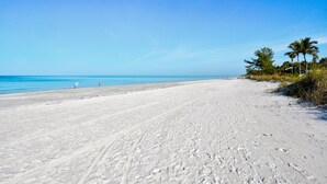 A wide, sandy beach with clear blue water and a few palm trees on the right. - Breathtaking sunsets and sunrises! (Indian Rocks Beach)
