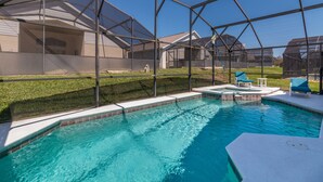 A swimming pool with a clear blue water, surrounded by a covered area with chairs and a small waterfall feature. - Sunshine Villa by VillaDirect (Kissimmee)