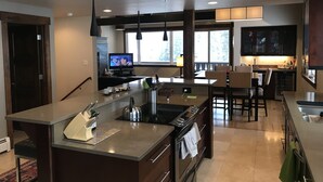 A modern kitchen with a central island, built-in oven, and a dining area with chairs.