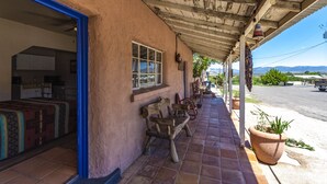 A covered patio with a rustic exterior, a wooden bench, and a potted plant. - Historic San Jose House Room 2 Wyatt Earp (Tombstone)