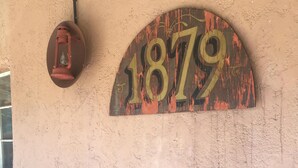 A rustic wall with a weathered sign reading "1879" and a lantern. - Historic San Jose House Room 2 Wyatt Earp (Tombstone)