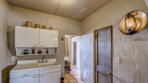 A kitchen with white cabinets, a sink, and a light fixture. - Stay at the Historic San Jose House Room 4 Doc Holliday (Tombstone)