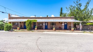 A two-story building with a flat roof, a porch with potted plants, and a blue door. - Stay at the Historic San Jose House Room 4 Doc Holliday (Tombstone)