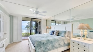 A bedroom with a bed, a dresser, a mirror, and a ceiling fan.