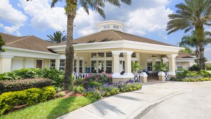 A two-story building with a covered porch, palm trees, and a variety of colorful flowers. - Sable Palms Villa by VillaDirect (Kissimmee)