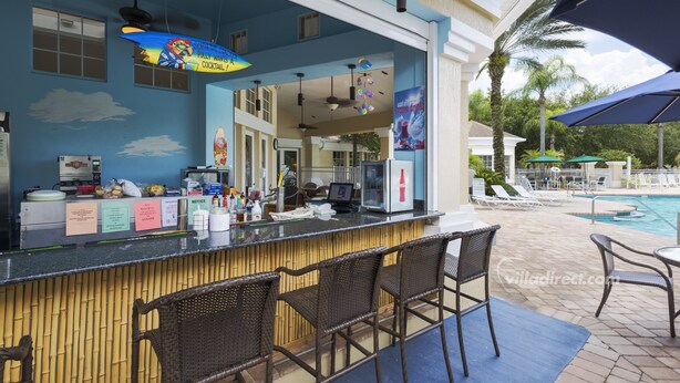 A bar area with a counter, bar stools, and a poolside view. - Sable Palms Villa by VillaDirect (Kissimmee)