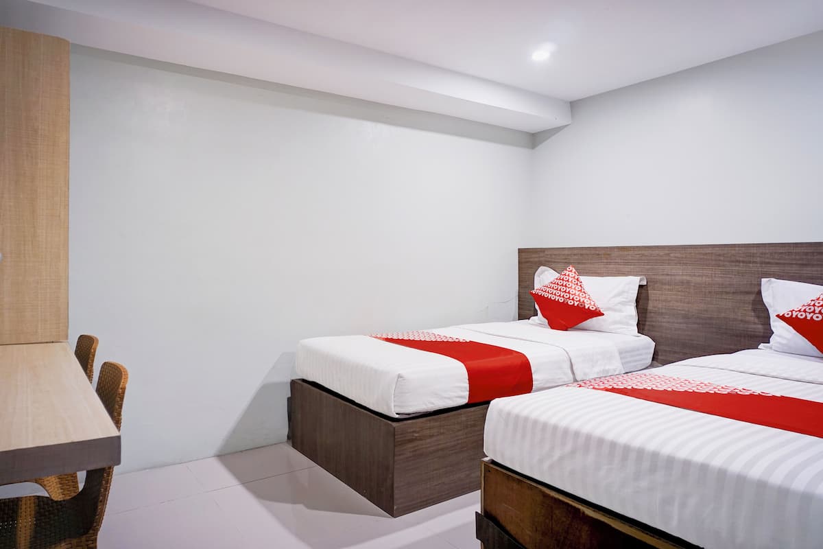 A hotel room with two beds, a wooden table, and a chair.