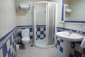A bathroom with a toilet, a glass shower enclosure, and a sink. - Hostal Tic-Tac (Mocejon)