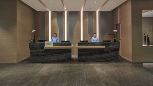 A reception area with two receptionists, a marble reception desk, and modern lighting. - Fairfield by Marriott Bintulu Paragon (Bintulu)