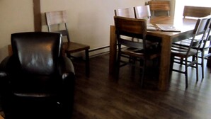A dining area with a wooden table and chairs, a clock on the wall, and a hanging light fixture. - Paintbrush Grande - spacious & comfortable, perfect for families (West Yellowstone)