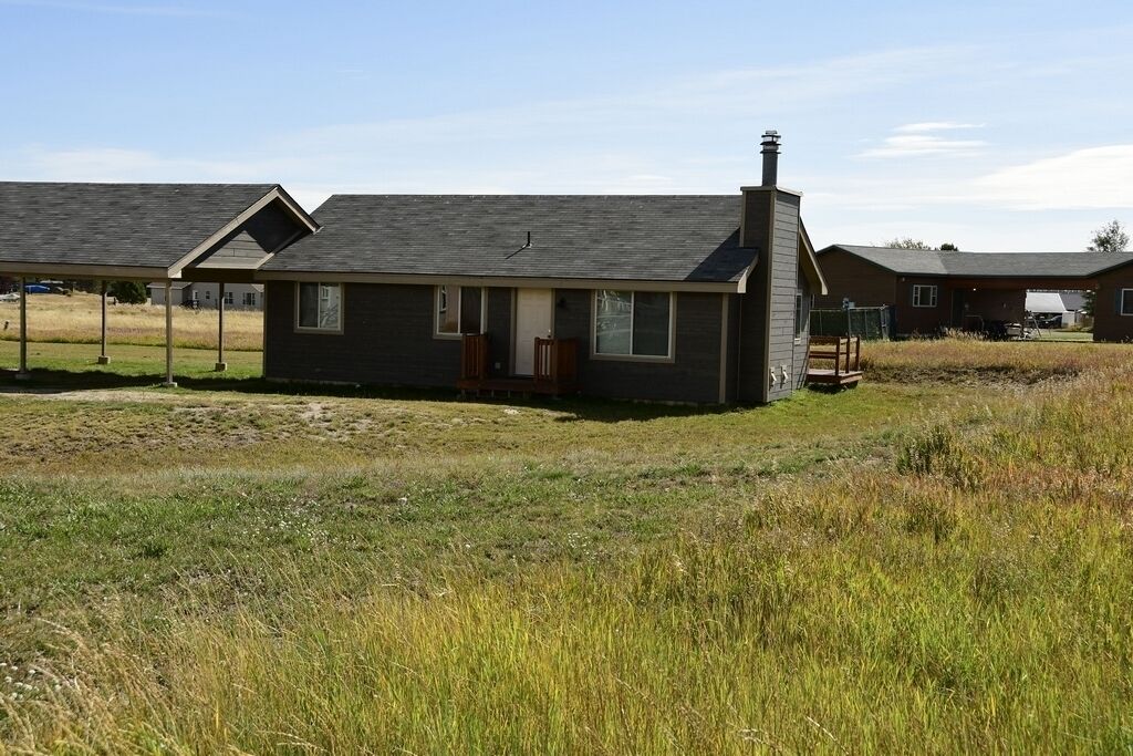 A single-story house with a sloped roof, a chimney, and a small porch. - Sandhill West Home - comfortable family retreat with great views (West Yellowstone)