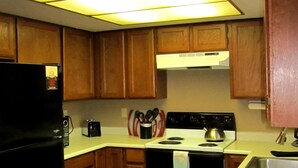 A kitchen with wooden cabinets, a black refrigerator, a stove, and a sink. - Sandhill West Home - comfortable family retreat with great views (West Yellowstone)