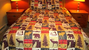 A bed with a quilt featuring animal and tree patterns, flanked by two bedside tables with lamps. - Sandhill West Home - comfortable family retreat with great views (West Yellowstone)