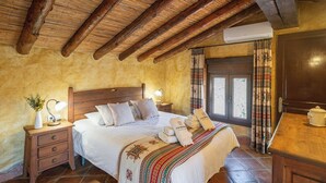 A cozy bedroom with a wooden bed, a nightstand with a lamp, and a window with curtains. - Finca Algarabia Cómpeta by Ruralidays (Málaga)