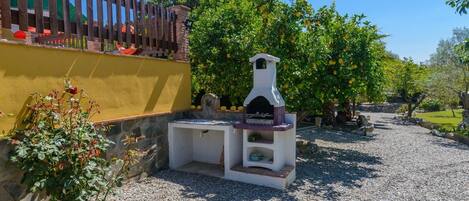 An outdoor kitchen area with a stone countertop and a white oven, surrounded by gravel and greenery.