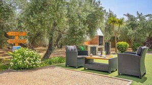 Un espace extérieur aménagé avec des meubles en osier, un barbecue et un panneau indiquant la présence d’une piscine.