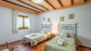 Une chambre avec deux lits, une fenêtre avec des rideaux, une table de chevet et une lampe.