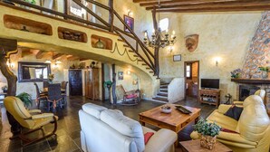 A spacious living area with a high ceiling, a wooden staircase, and a fireplace.