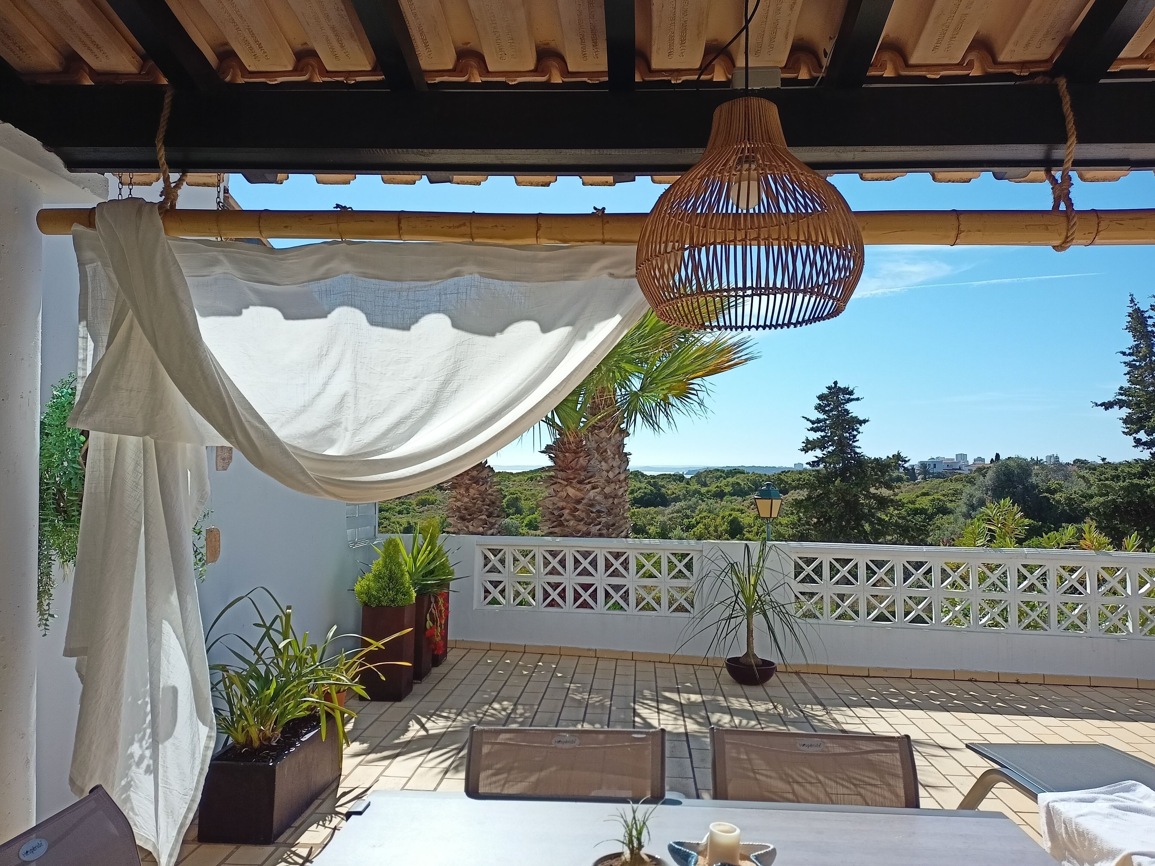 Un espacio de estar al aire libre cubierto con una mesa, sillas y plantas en macetas.