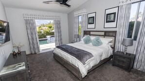 A bedroom with a bed, bedside tables, a ceiling fan, and a view of the outdoors. - FONDA RETREAT VRBO 3 (Palm Desert)