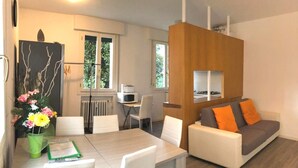 A modern living room with a dining area, a sofa with orange cushions, and a wooden partition. - Venice Romantic Views Ca' Crea (Venice)