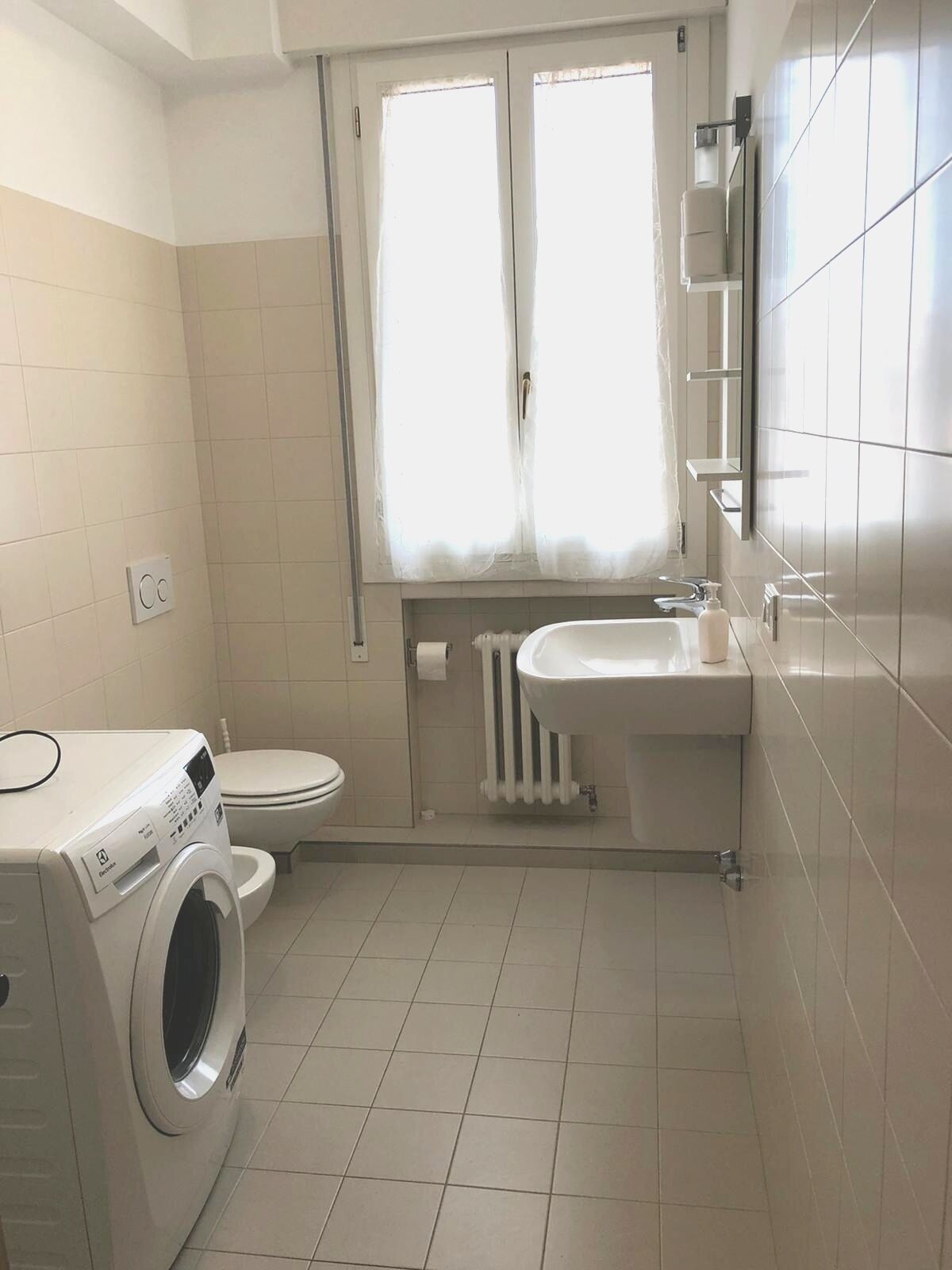 Une petite salle de bain équipée d’un lave-linge, de toilettes et d’un lavabo.
