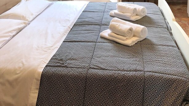 A hotel room with a bed, a small table with a lamp, a chair, and a view of the outdoors through an open door. - Venice Romantic Views Ca' Crea (Venice)