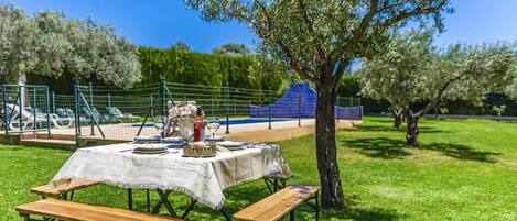 An outdoor dining setup with a table, benches, and a blue fence in the background.