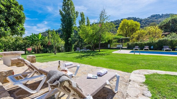 Un pati amb piscina, gandules de pedra i taula de pedra.